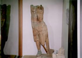 顔の部分がなく、胸から下の体の部分が展示されている仏像（天部形立像）の残欠の写真
