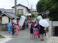 道路に大きな提灯が下げられ、浴衣姿の人達が集まっている甲植木区男の地蔵女の地蔵の様子の写真