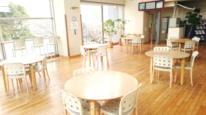 丸テーブルと白椅子が沢山設置されている開放感のある明るい室内（憩いの場）の写真