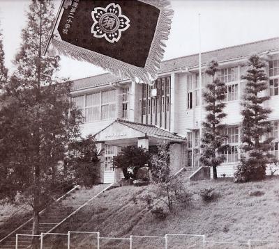 コンクリートの階段の横に土手があり、2階建て校舎が建っている須恵第二小学校の白黒写真